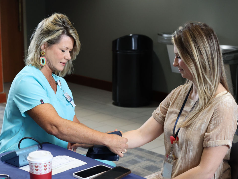 nurse educator slips on a blood pressure cuff during a health screening